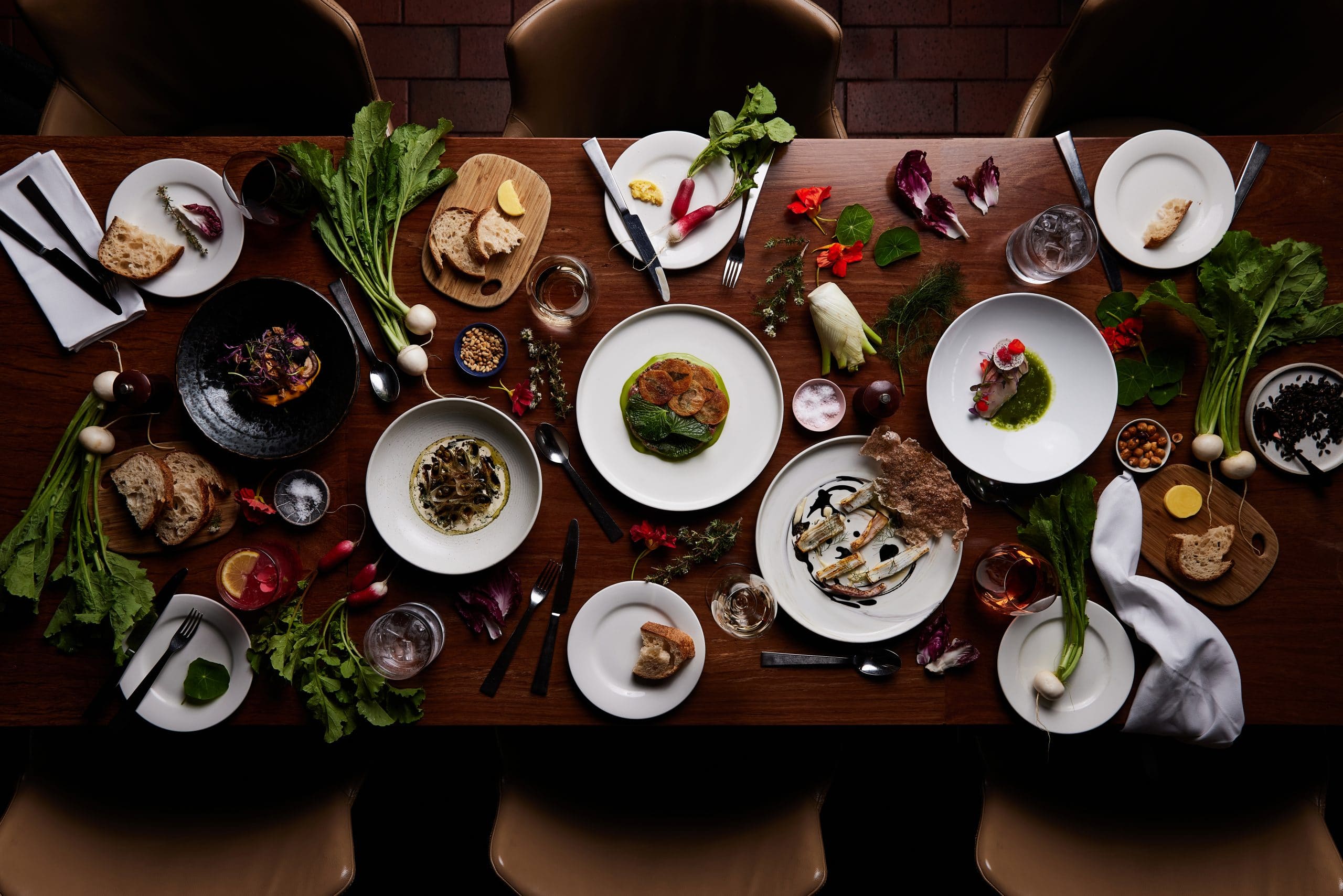 A table filled with a variety of plates containing delicious food and an assortment of colourful vegetables.