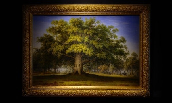 A painting of a tree in a gold frame, hanging in a dark room with a dim light above the painting