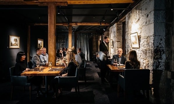 A sophisticated dining setting of the Landscape Restaurant at Henry Jones, featuring people seated at tables